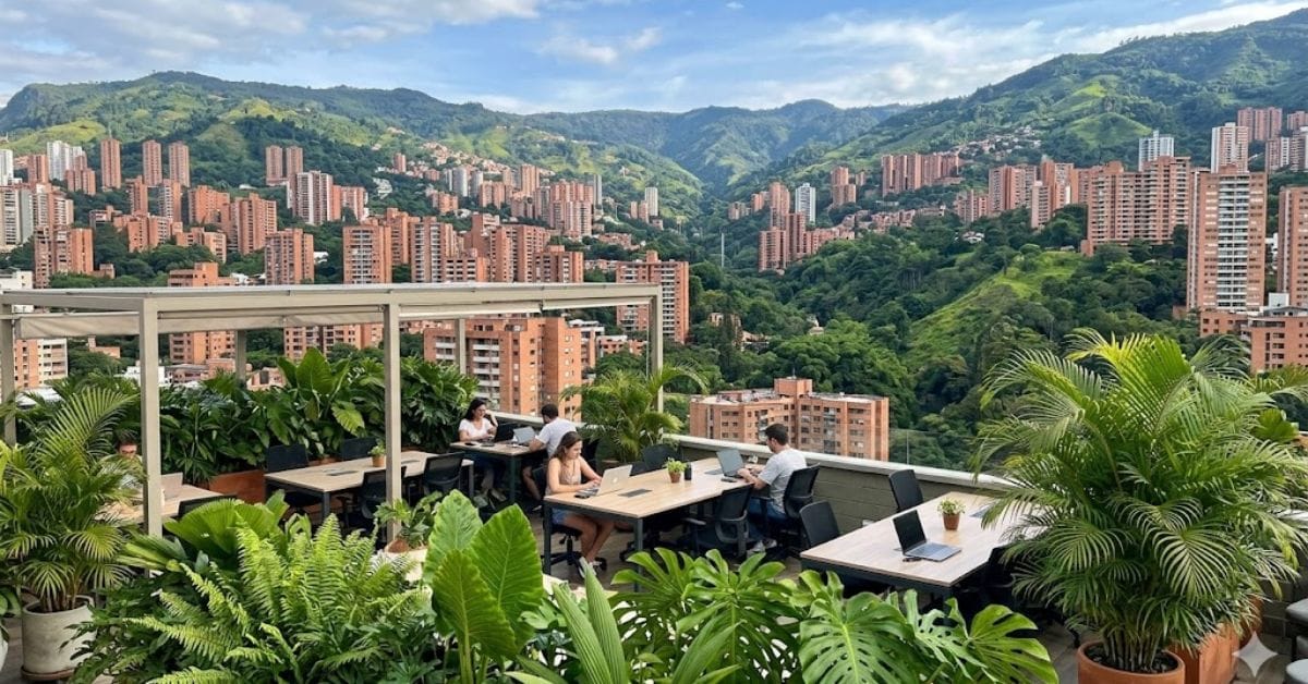 A rooftop balcony workspace in Medellín, Colombia, with a panoramic view of the city and hills.
