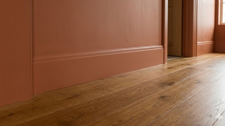 Warm wood flooring matching perfectly with colour drenched terracotta baseboards