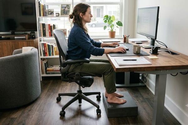 A yoga block used under a desk as a footrest to fix screen motion sickness through body grounding.