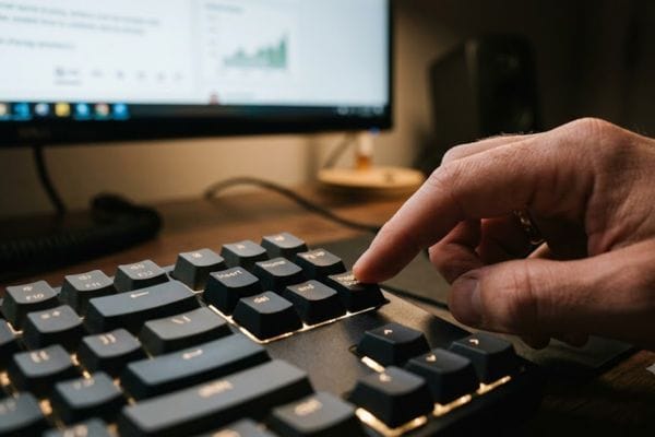 A hand pressing the page down key on a keyboard to fix screen motion sickness caused by continuous mouse scrolling.